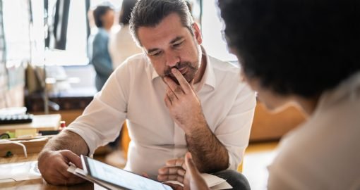 Mature man looking at a digital tablet that a colleague is showing at work