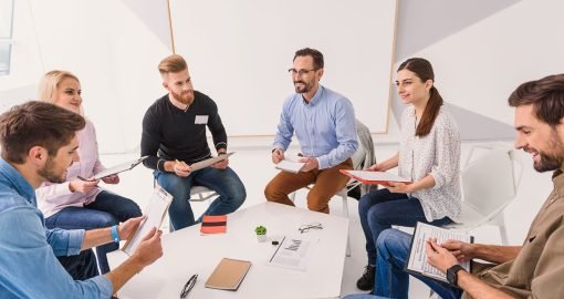 Smile will save world. Cheerful visitors are in light room, sitting around table and speaking